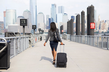 Businesswoman with wheeled luggage on ferry pier Stock Photo - Premium Royalty-Free, Code: 614-09178315