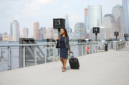 Businesswoman with wheeled luggage on ferry pier Stock Photo - Premium Royalty-Free, Code: 614-09178316