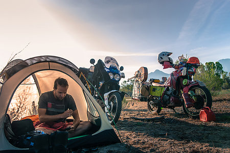 Biker using mobile phone inside tent, Fresno, California, USA Stock Photo - Premium Royalty-Free, Code: 614-09183007