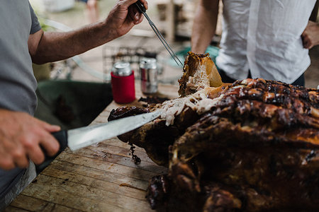 preparing party home - Man slicing hog roast on table, cropped Stock Photo - Premium Royalty-Free, Code: 614-09183025