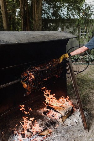 preparing party home - Man rotating hog roast spit in garden, cropped Stock Photo - Premium Royalty-Free, Code: 614-09183023