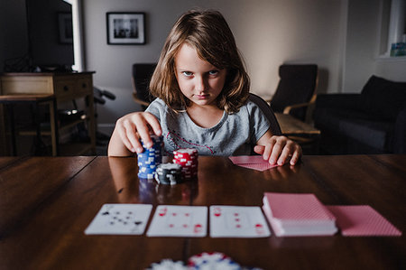 Girl with stack of gambling chips playing cards at table, portrait Stock Photo - Premium Royalty-Free, Code: 614-09183034