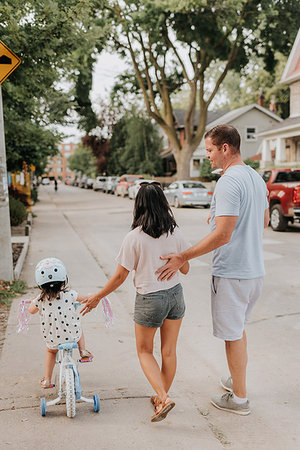 Family walking with daughter on tricycle Stock Photo - Premium Royalty-Free, Code: 614-09198256