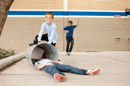 Two boys bullying another, one boy in dustbin Stock Photo - Premium Royalty-Free, Code: 614-09209989