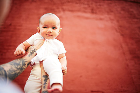 simsearch:649-08564294,k - Father holding baby boy against red background, low angle view Stock Photo - Premium Royalty-Free, Code: 614-09210148