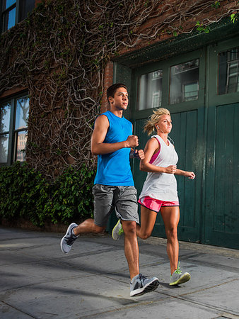 Young man and young woman running on urban street Stock Photo - Premium Royalty-Free, Code: 614-09210218
