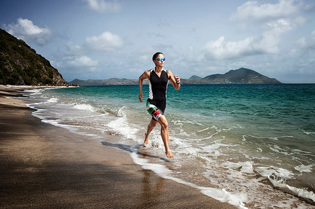 female triathlon - Mid adult triathlete running on beach Stock Photo - Premium Royalty-Free, Code: 614-09210281