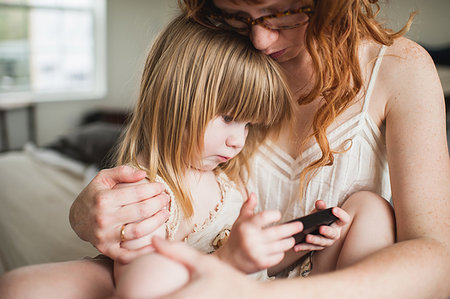 simsearch:614-09210319,k - Mother hugging daughter, using smartphone Photographie de stock - Premium Libres de Droits, Code: 614-09210317