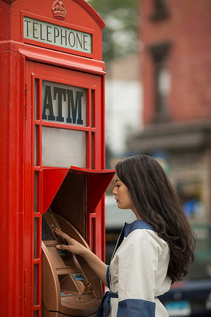 Mid adult women using cash machine in a public telephone box Stock Photo - Premium Royalty-Free, Code: 614-09210334