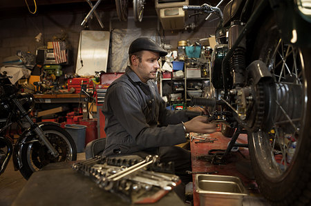 dirty overalls pictures - Mechanic in his garage converting gas powered motorcycles to Bio-Diesel Stock Photo - Premium Royalty-Free, Code: 614-09210629