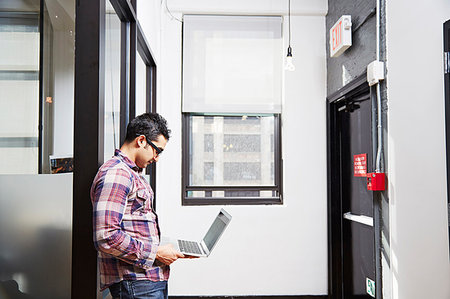 simsearch:614-06403067,k - Young man holding laptop in corridor Stock Photo - Premium Royalty-Free, Code: 614-09210925