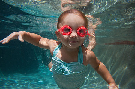 Underwater portrait of girl learning to swim and smiling at camera Stock Photo - Premium Royalty-Free, Code: 614-09211923