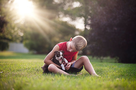 simsearch:614-03020295,k - Front view of boy sitting on grass holding Boston Terrier puppy, looking down Fotografie stock - Premium Royalty-Free, Codice: 614-09212161