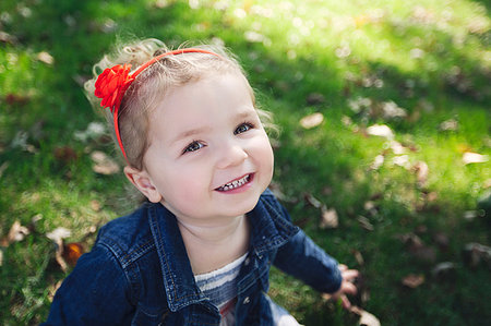 simsearch:614-09056681,k - High angle portrait of girl with red hairband wearing denim jacket looking at camera smiling Fotografie stock - Premium Royalty-Free, Codice: 614-09212241