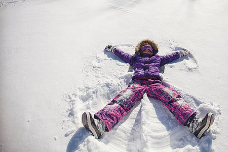 High angle view of girl wearing ski suit lying snow making snow angel Photographie de stock - Premium Libres de Droits, Code: 614-09212257