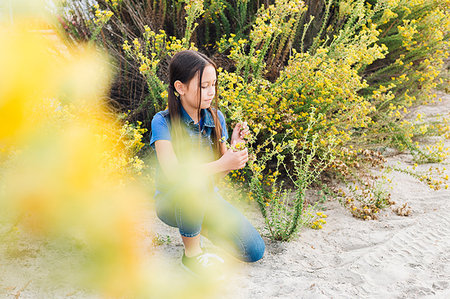 Girl kneeling to smell plant Stock Photo - Premium Royalty-Free, Code: 614-09213812