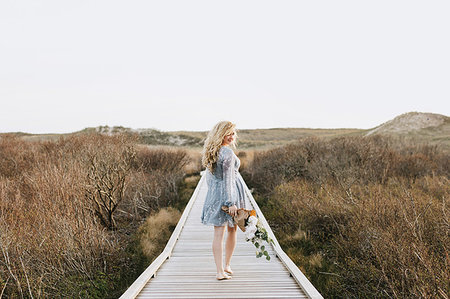 Young woman carrying bunch of flowers on coastal dune boardwalk,  Menemsha, Martha's Vineyard, Massachusetts, USA Photographie de stock - Premium Libres de Droits, Code: 614-09232117