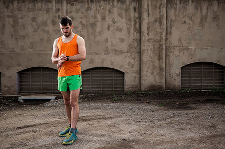 people wearing tennis shoes - Young male runner checking smartwatch in front of urban wall Stock Photo - Premium Royalty-Free, Code: 614-09245234