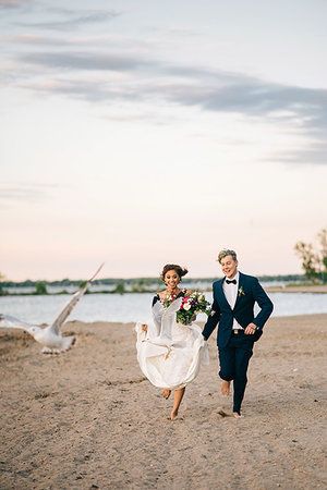 Romantic bride and groom running barefoot on lakeside, Lake Ontario, Toronto, Canada Stock Photo - Premium Royalty-Free, Code: 614-09245310