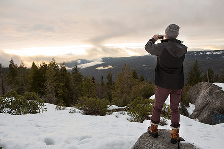 Mid adult man photographing view from rock on snow covered mountain, rear view, Twain Harte, California, USA Stock Photo - Premium Royalty-Free, Code: 614-09245418