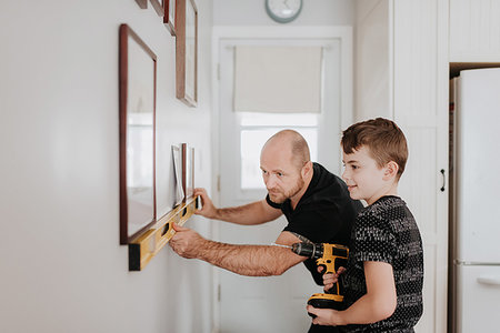 drilling wall - Father teaching son drill wall for picture frames Stock Photo - Premium Royalty-Free, Code: 614-09249605
