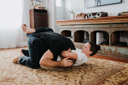 Couple wrestling on carpet at home Stock Photo - Premium Royalty-Free, Code: 614-09249636