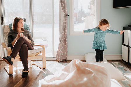 simsearch:649-09250257,k - Mother watching toddler daughter jumping on cushions on living room floor Stock Photo - Premium Royalty-Free, Code: 614-09249700