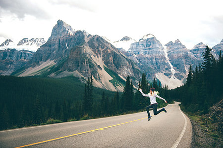Woman jumping in mid air on road, Jasper, Canada Stock Photo - Premium Royalty-Free, Code: 614-09249820