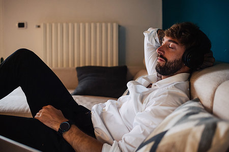 simsearch:614-08983600,k - Mid adult man reclining on sofa listening to headphones with eyes closed Foto de stock - Sin royalties Premium, Código: 614-09258535