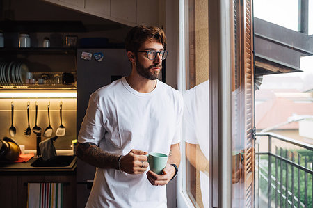 simsearch:695-05772524,k - Mid adult man with coffee cup gazing out through apartment window Foto de stock - Royalty Free Premium, Número: 614-09258543