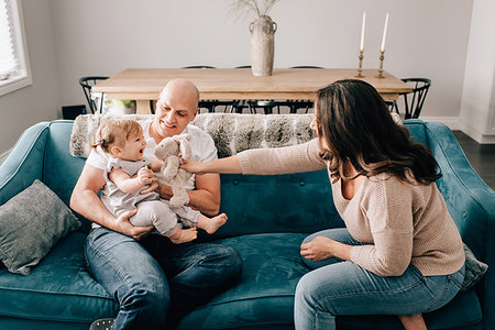 simsearch:614-08270474,k - Mother and father on sofa with baby daughter playing with soft toy Photographie de stock - Premium Libres de Droits, Code: 614-09258609