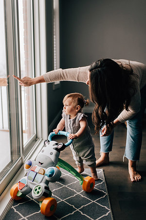 Mother with baby daughter looking out through patio door Stock Photo - Premium Royalty-Free, Code: 614-09258603