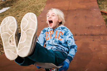 Boy sitting and skateboarding backwards down wooden skateboard ramp Foto de stock - Sin royalties Premium, Código: 614-09258748