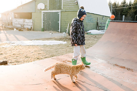 simsearch:614-09258754,k - Boy with cat looking at farmyard skateboard ramp Photographie de stock - Premium Libres de Droits, Code: 614-09258756