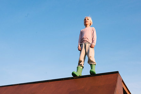 simsearch:614-09258754,k - Boy standing on top of skateboard ramp against blue sky, low angle view Photographie de stock - Premium Libres de Droits, Code: 614-09258764