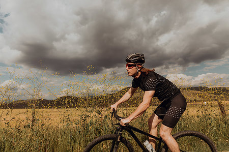 simsearch:614-09259136,k - Young male cyclist cycling on rural road, side view, Exeter, California, USA Fotografie stock - Premium Royalty-Free, Codice: 614-09259114