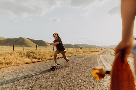 simsearch:649-08548886,k - Young barefoot male skateboarder skateboarding on rural road, girlfriend watching, Exeter, California, USA Photographie de stock - Premium Libres de Droits, Code: 614-09259125