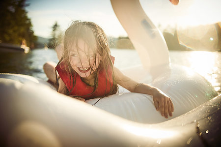 Girl playing on inflatable swan in lake Stock Photo - Premium Royalty-Free, Code: 614-09253715