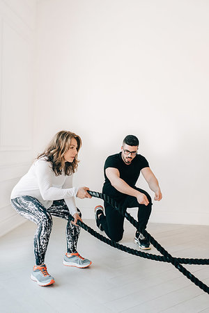 simsearch:614-07032221,k - Fitness instructor observing woman using battle rope in studio Stock Photo - Premium Royalty-Free, Code: 614-09276255