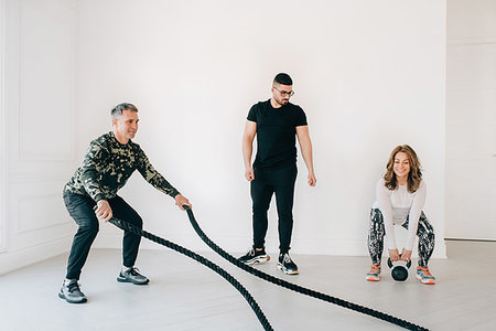 simsearch:614-06403131,k - Fitness instructor observing man using battle rope in studio Photographie de stock - Premium Libres de Droits, Code: 614-09276259