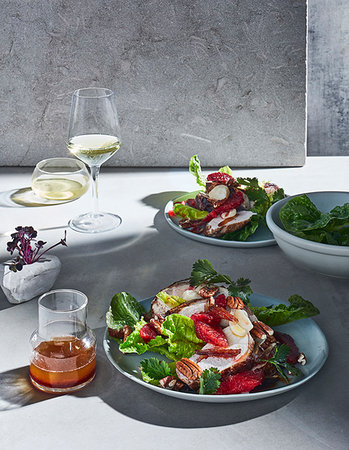 simsearch:649-07239249,k - High key still life with glasses of white wine and plates of spiced chicken, blood orange and date salad on white table Photographie de stock - Premium Libres de Droits, Code: 614-09276402