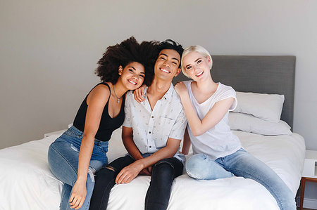 simsearch:614-09276991,k - Happy young man and two female friends sitting on bed, portrait Stock Photo - Premium Royalty-Free, Code: 614-09276599