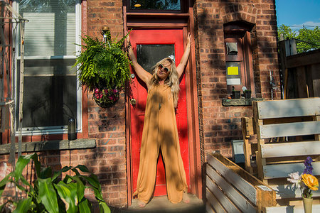 simsearch:614-08827383,k - Mid adult woman posing in doorway with arms raised at community garden party, portrait Photographie de stock - Premium Libres de Droits, Code: 614-09276816