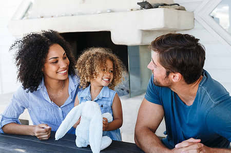 family beach house - Couple talking and playing with daughter in beach house Stock Photo - Premium Royalty-Free, Code: 614-09276838