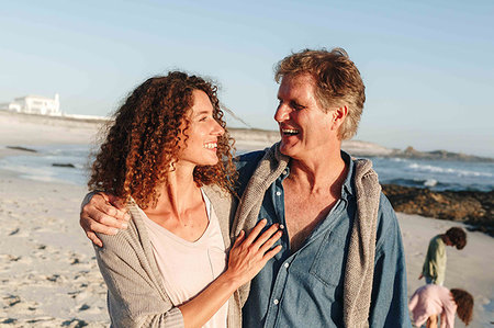 simsearch:649-09252159,k - Couple taking walk on sandy beach, children in background Stock Photo - Premium Royalty-Free, Code: 614-09276955