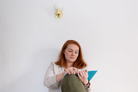 simsearch:614-06312057,k - Young woman with red hair sitting and reading diary at home Stock Photo - Premium Royalty-Free, Code: 614-09276989