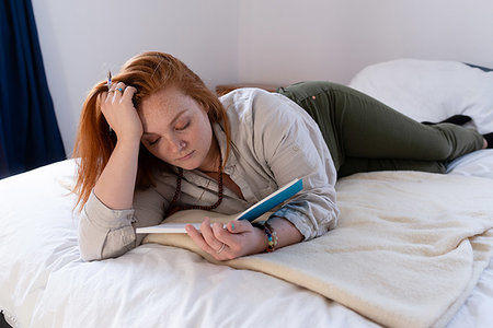 simsearch:614-06312057,k - Young woman with red hair lying on bed reading her diary Stock Photo - Premium Royalty-Free, Code: 614-09276993