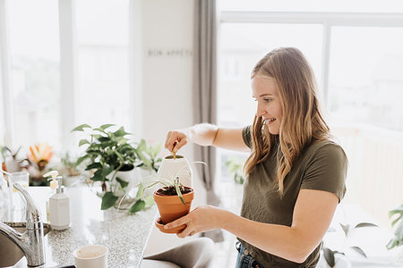 Woman watering house plants Stock Photo - Premium Royalty-Free, Code: 614-09277177