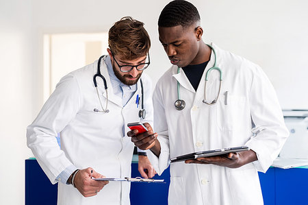 doctor wearing stethoscope - Doctors using smartphone at hospital reception Stock Photo - Premium Royalty-Free, Code: 614-09270070
