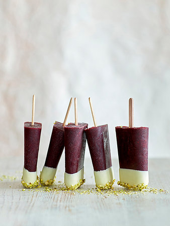 Tri-coloured ice lollies in a row on table, white background Fotografie stock - Premium Royalty-Free, Codice: 614-09270158